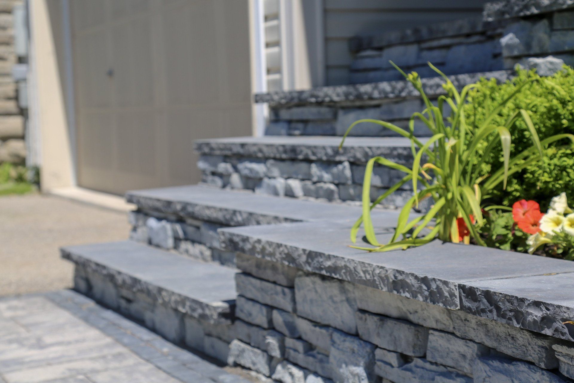 A stone wall surrounds a set of stairs leading up to a house.