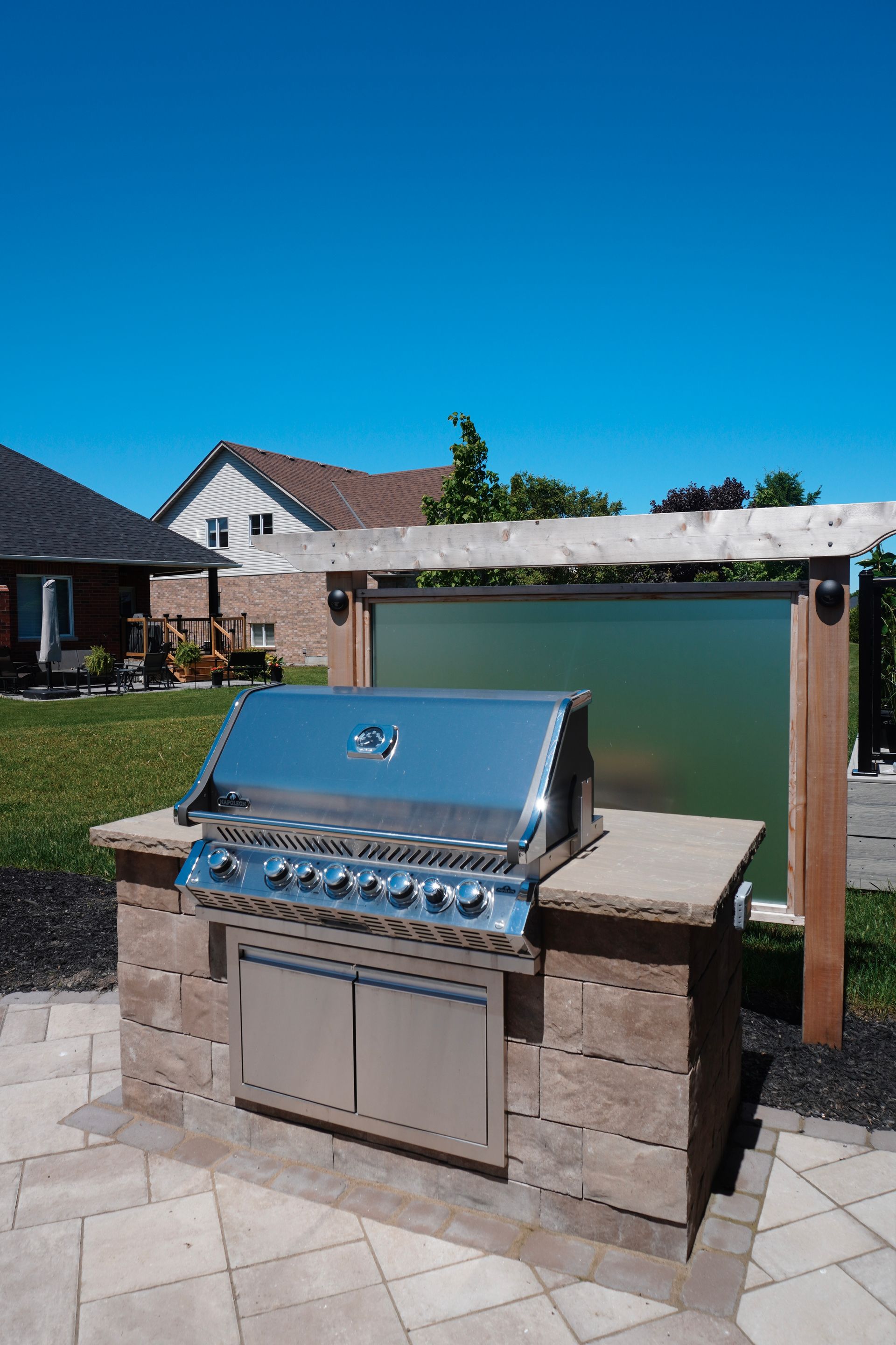 A stainless steel grill is sitting on a patio next to a house.