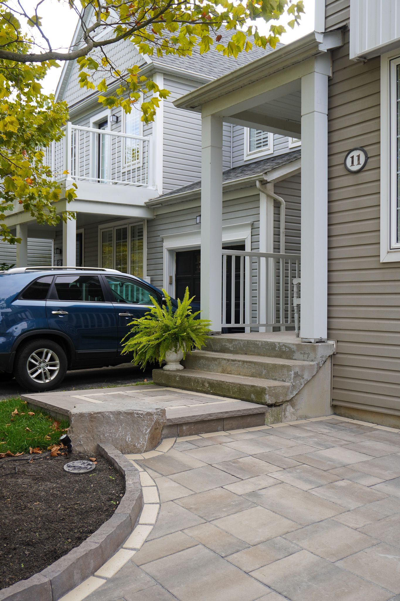 Blue car parked near a house with steps and a walkway. Number 17 visible on house.