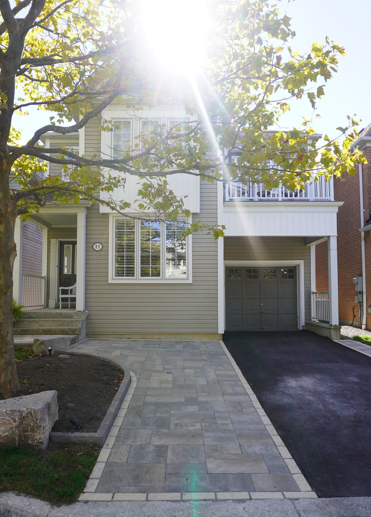 Two-story house with a driveway and walkway, sunny day. The garage door is closed.