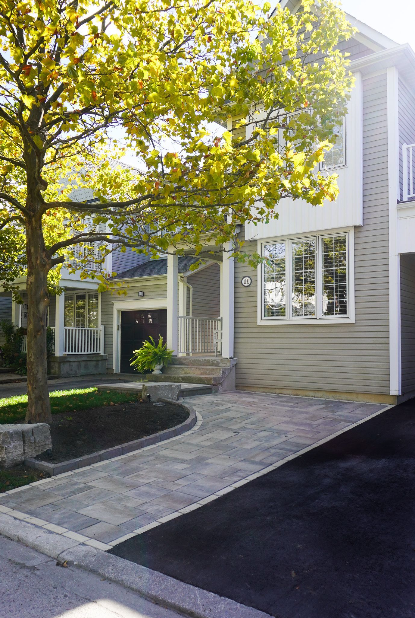 Exterior of a two-story home with a paved driveway and mature tree.