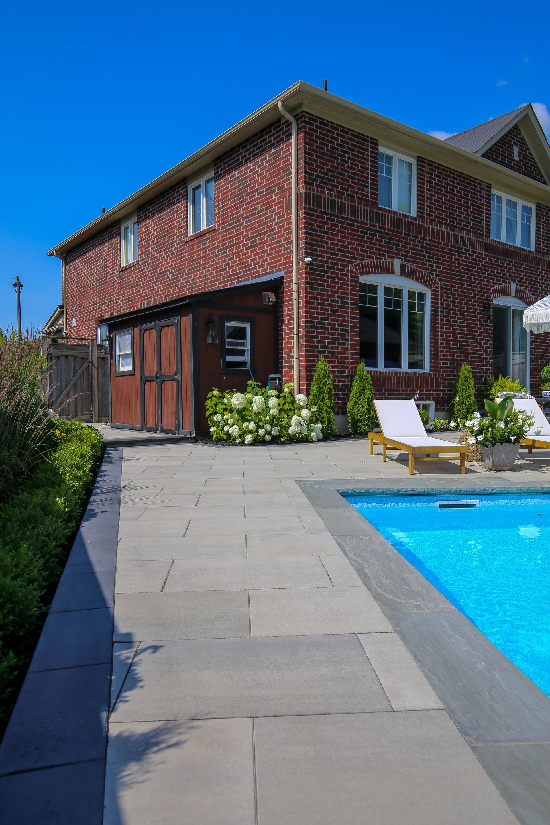 A large brick house with a swimming pool in front of it.
