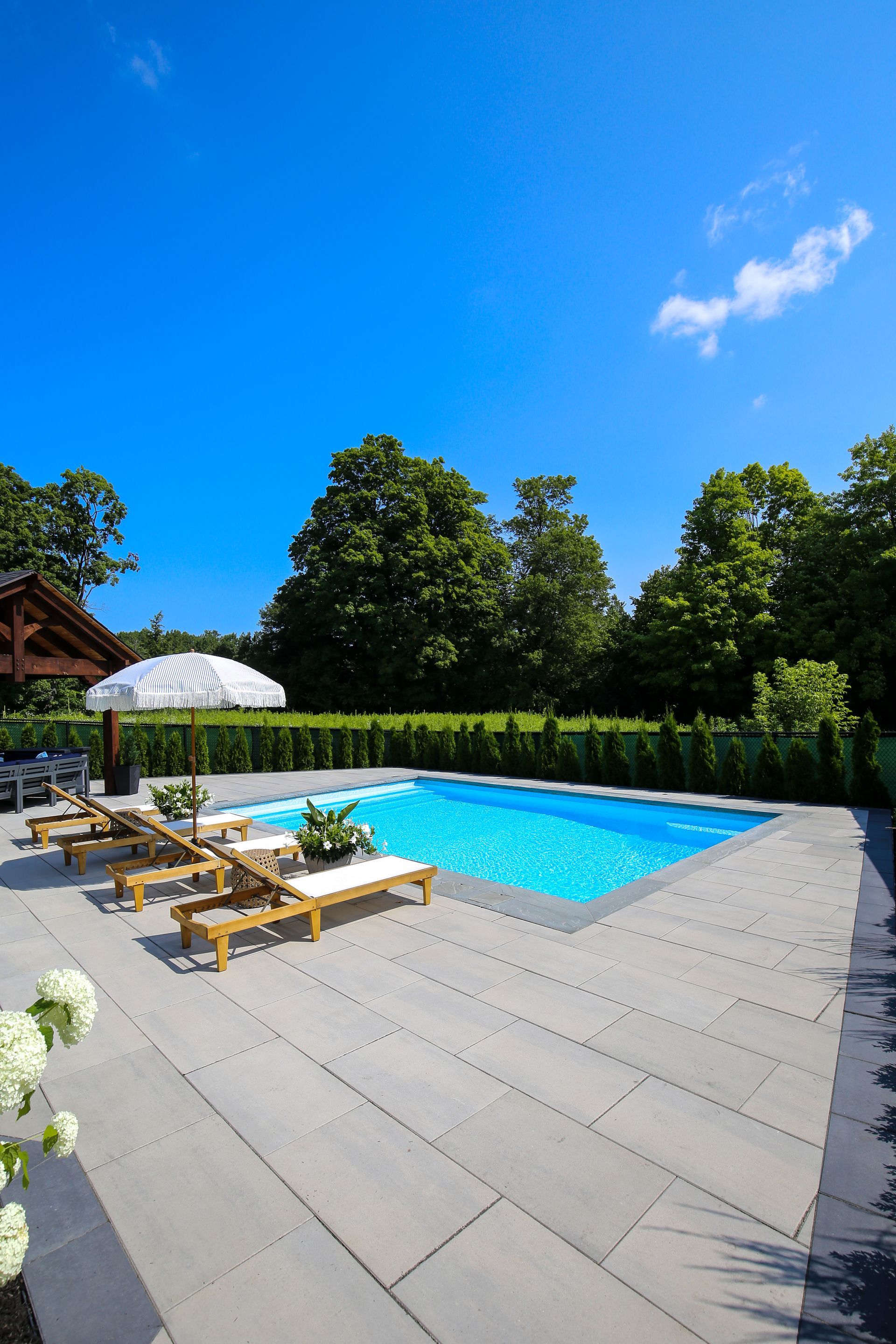A large swimming pool surrounded by chairs and umbrellas on a sunny day