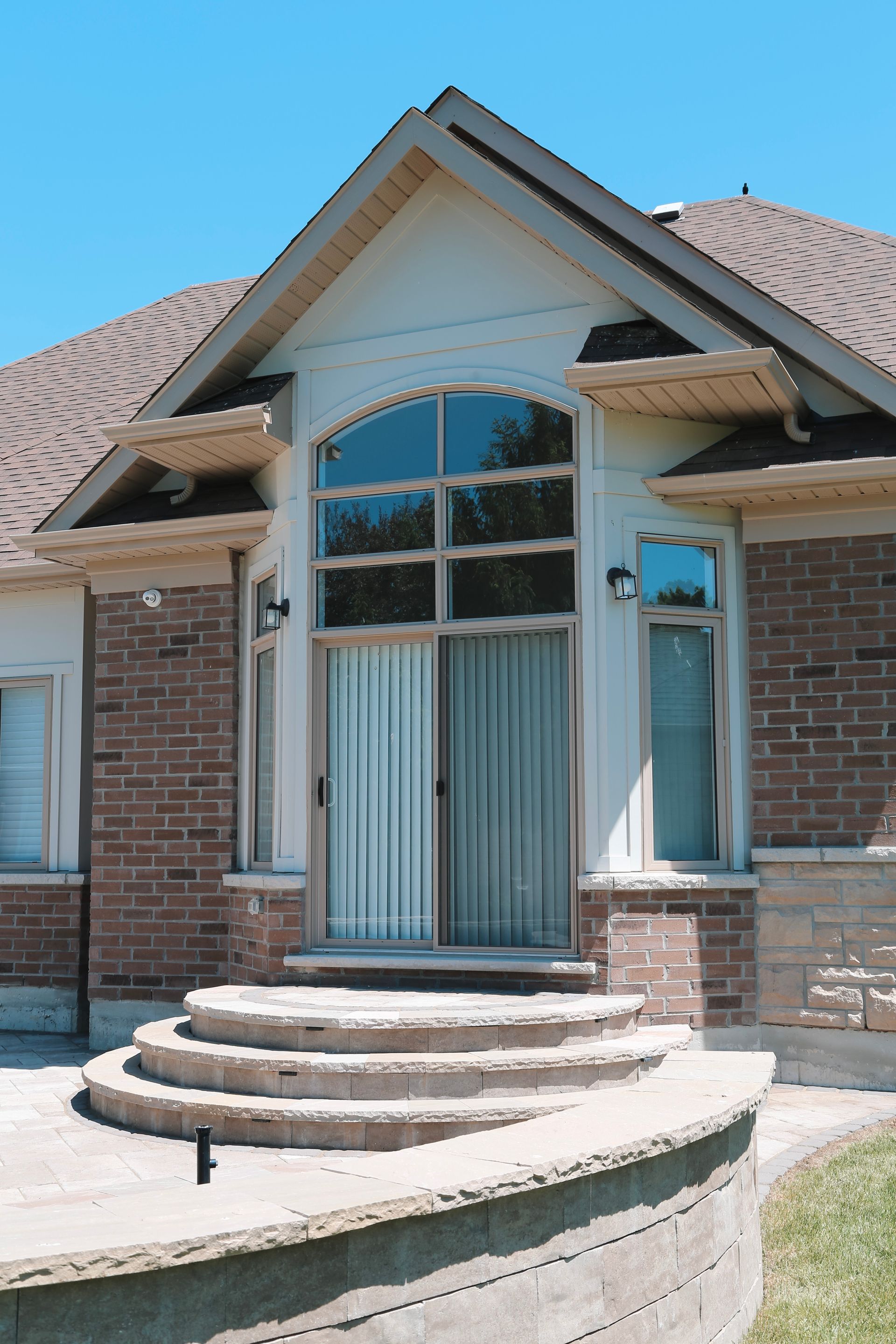 Brick home entrance with arched window and stone steps.