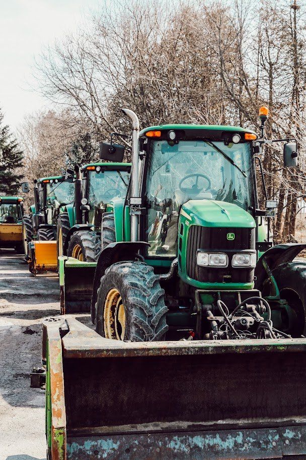 A row of green tractors are parked in a parking lot.