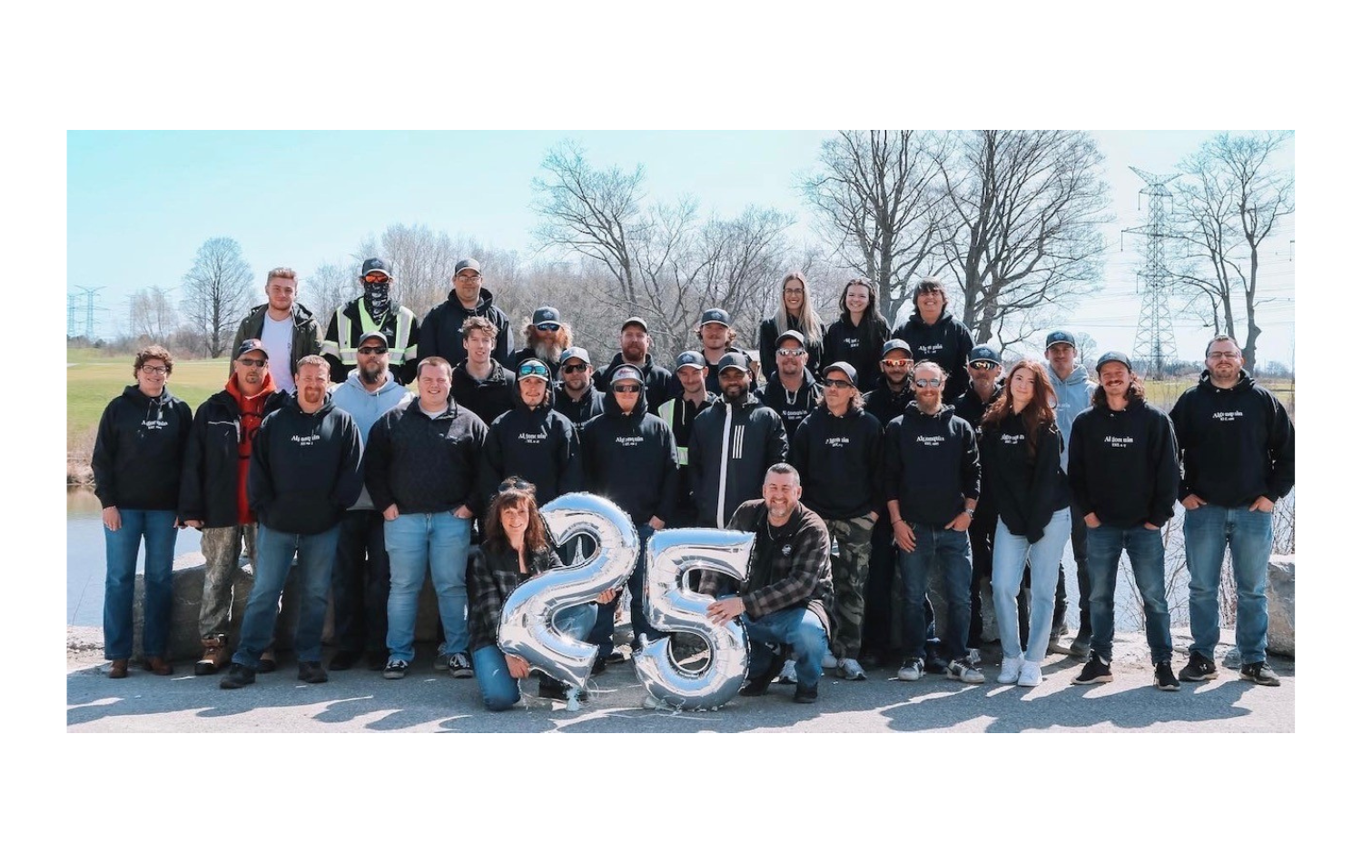 A group of people standing next to each other holding balloons that say 25.