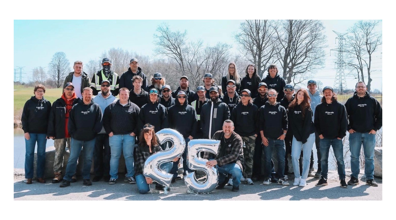 A group of people are posing for a picture with balloons that say 25.