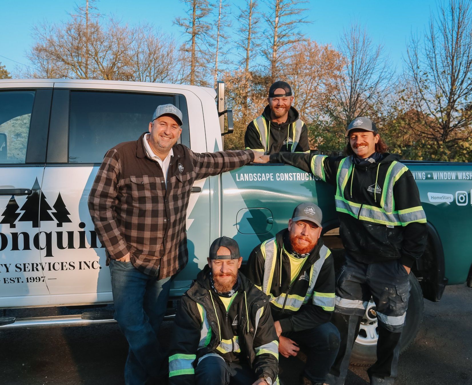 A group of men are posing for a picture in front of a truck that says landscape services inc.