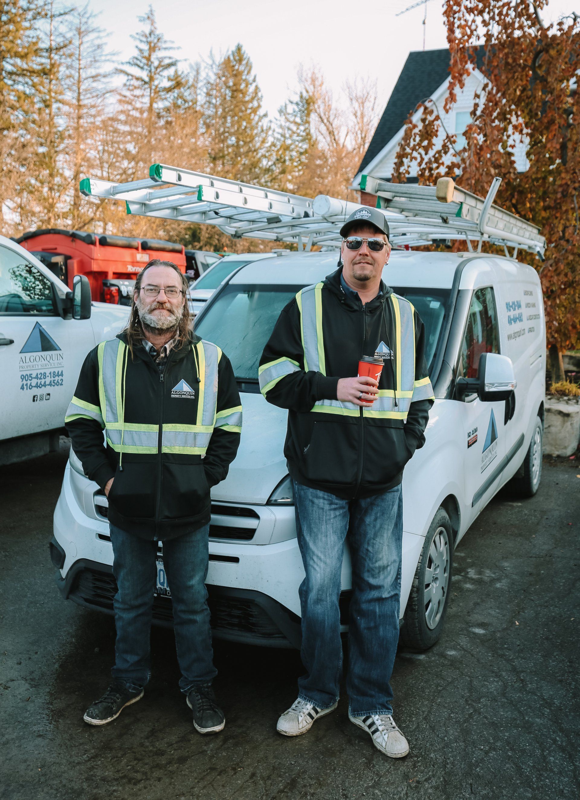 Two men are standing next to each other in front of a van.