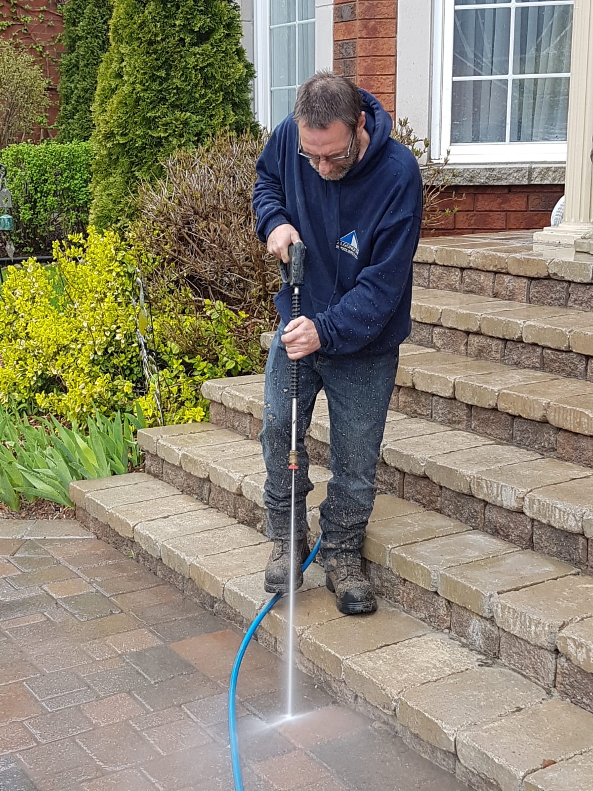 A man is using a pressure washer to clean the steps of a house.