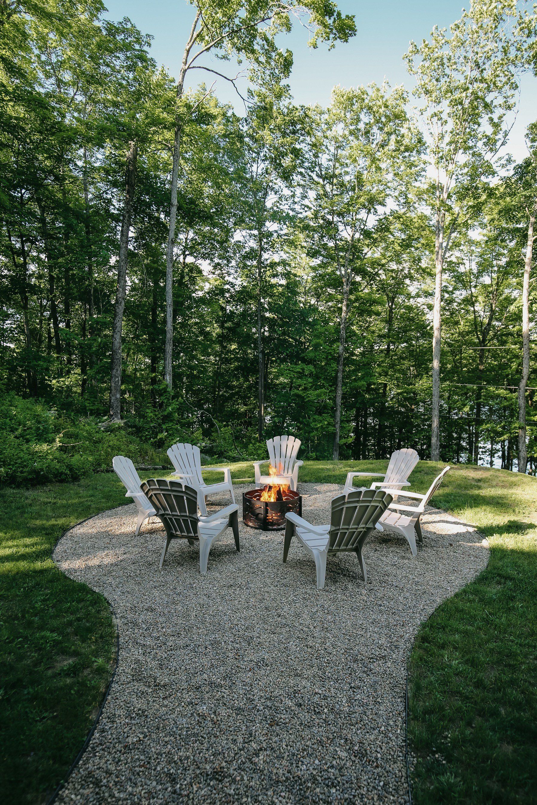 A group of chairs are sitting around a fire pit in a backyard.