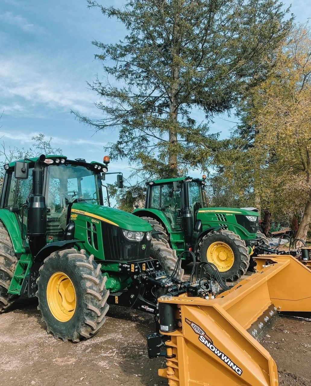 Two green tractors are parked next to each other in a field.