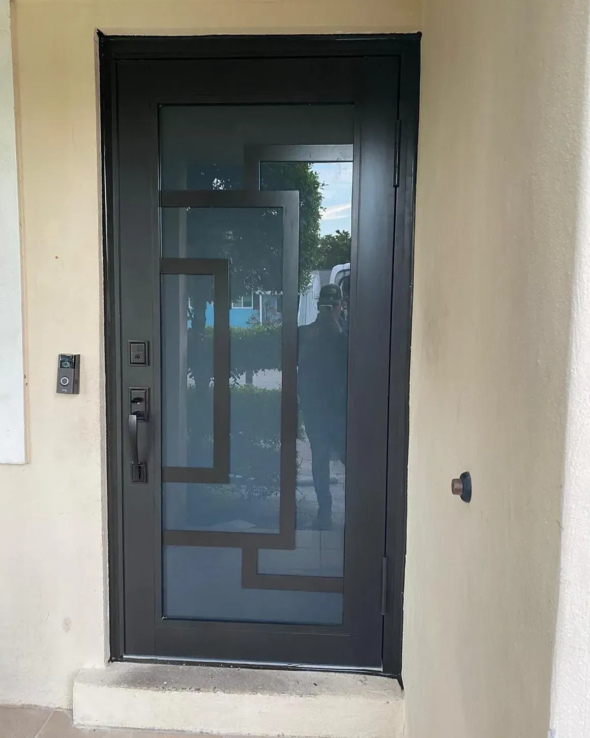 Black metal front door with geometric design and sidelight.