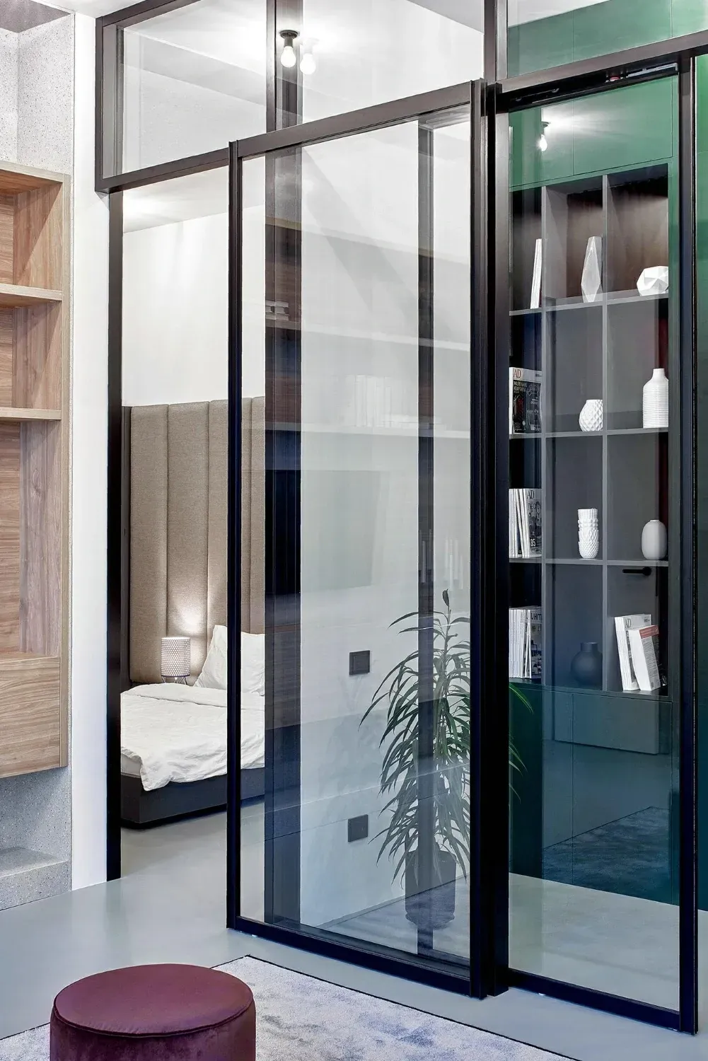 Unas puertas corredizas de cristal separan un dormitorio con una cama y una estantería empotrada.