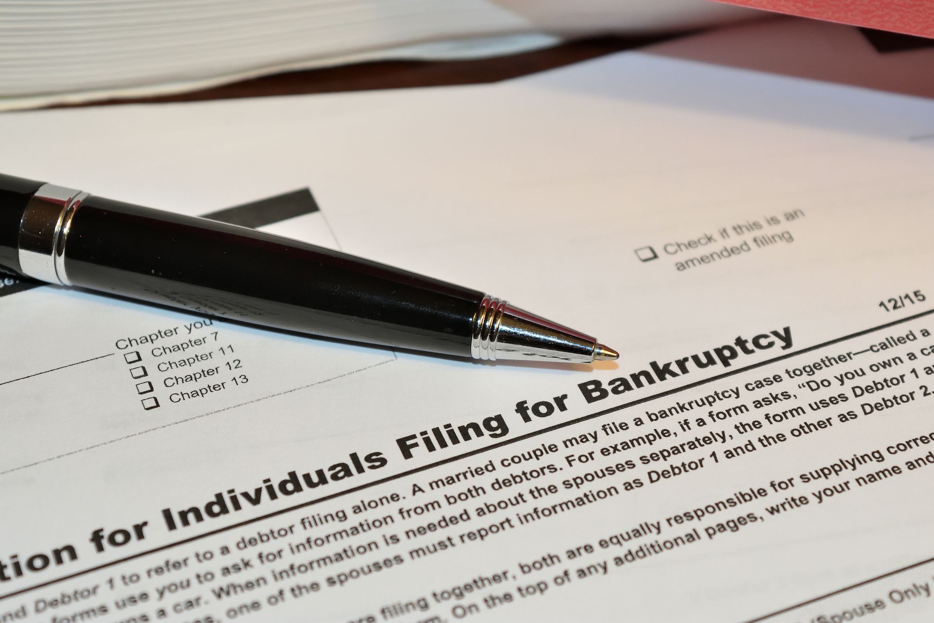Pen on “Petition for Individuals Filing for Bankruptcy” form with checklist visible.