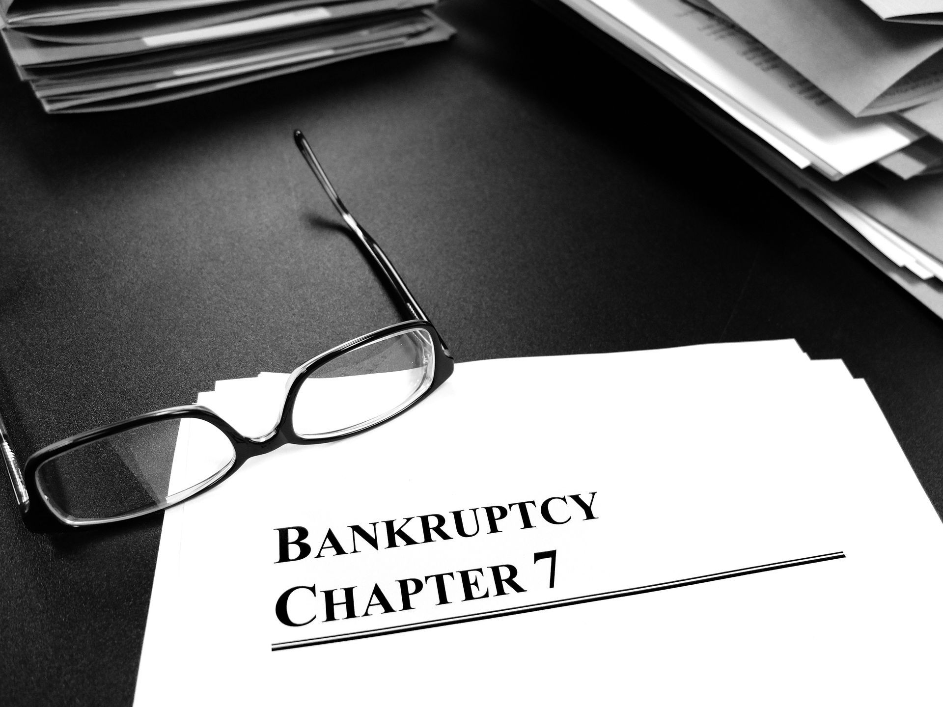 Bankruptcy Chapter 7 Documents on Desk with Glasses.