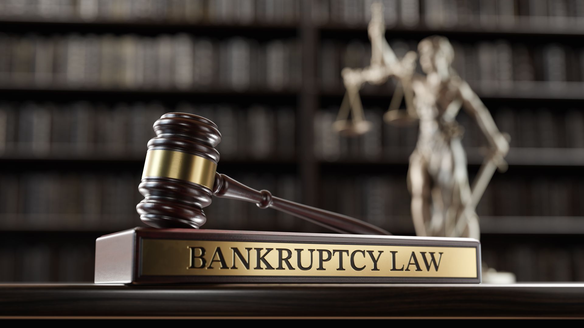 Judge’s gavel on bankruptcy law book with justice statue in library background.
