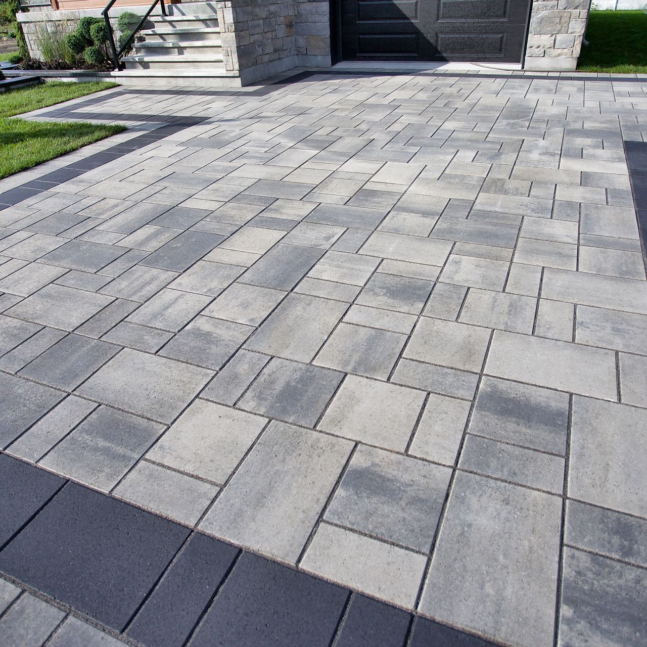 A gray and black brick driveway with a black border