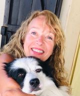 Una donna sorridente abbraccia un cane bianco e nero vicino a una porta.