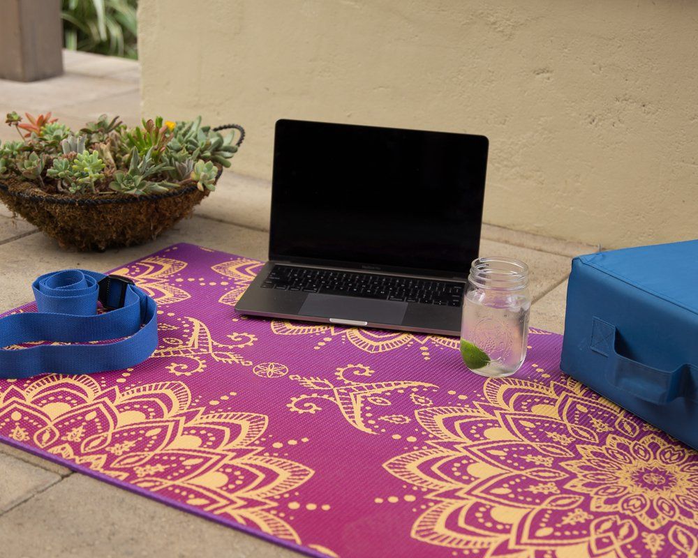 A laptop is sitting on top of a yoga mat.