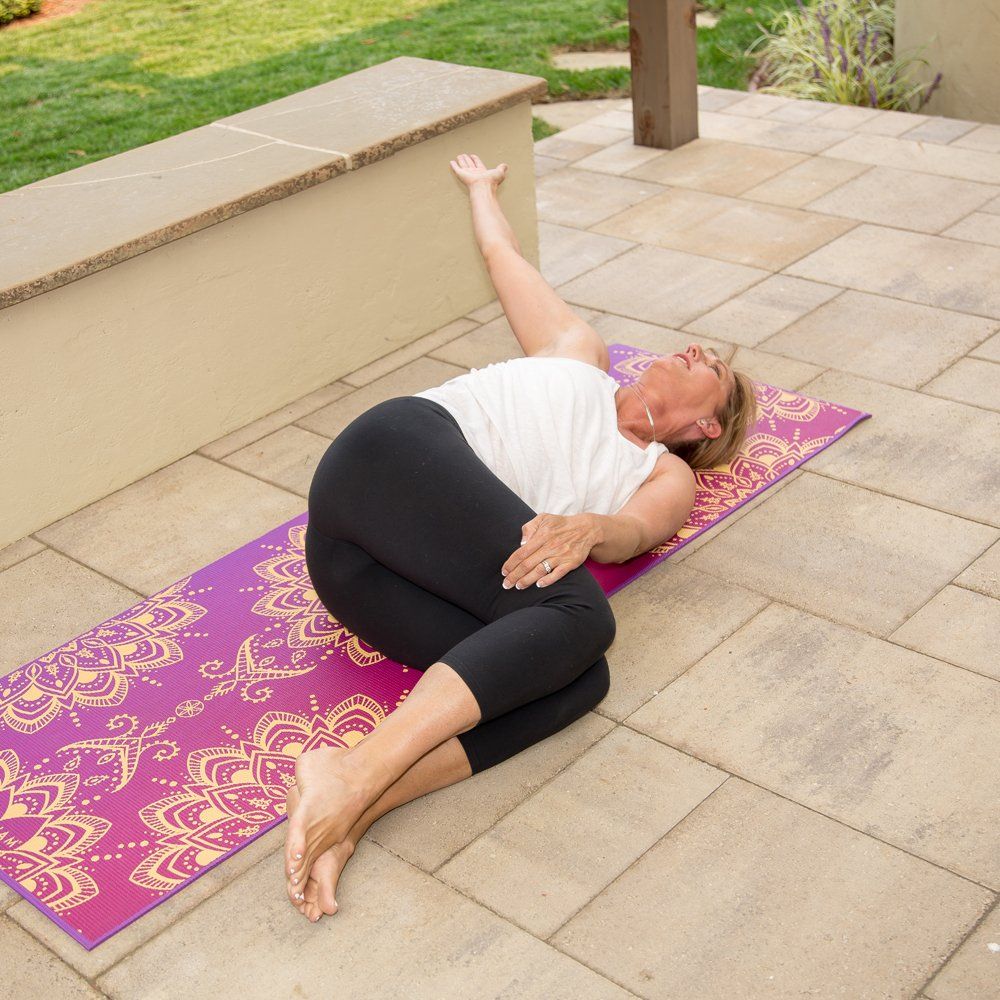 A woman is laying on a yoga mat with her legs crossed
