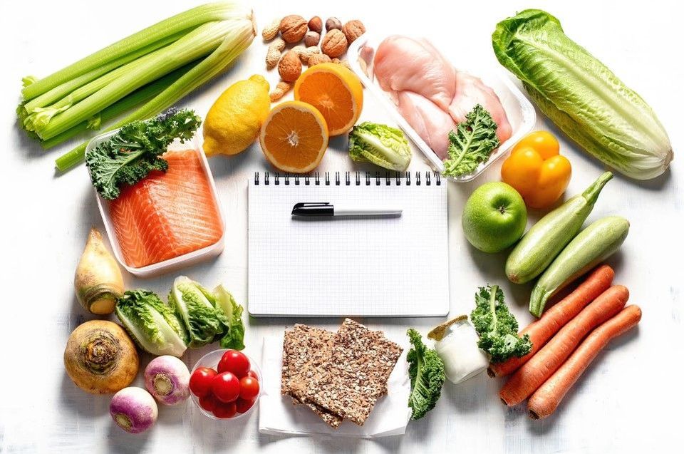 Fresh vegetables, fish and a notebook for planning a nutrition programme