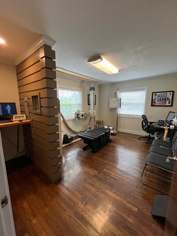 Living room with wood floors, gray sofa, exercise bike, wall art, and a desk by a brick partition