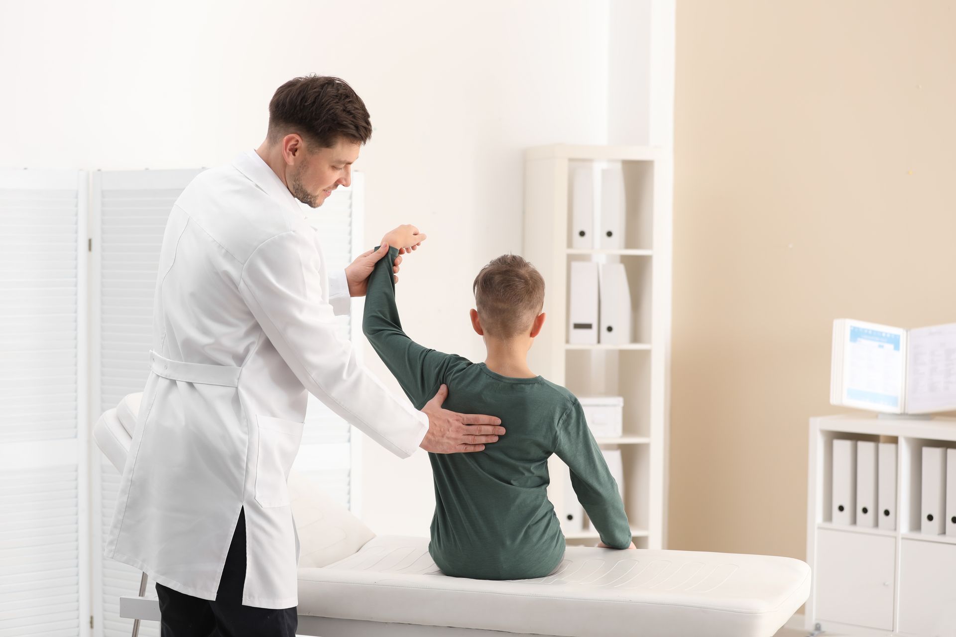 Doctor examining a child’s back in a bright clinic room