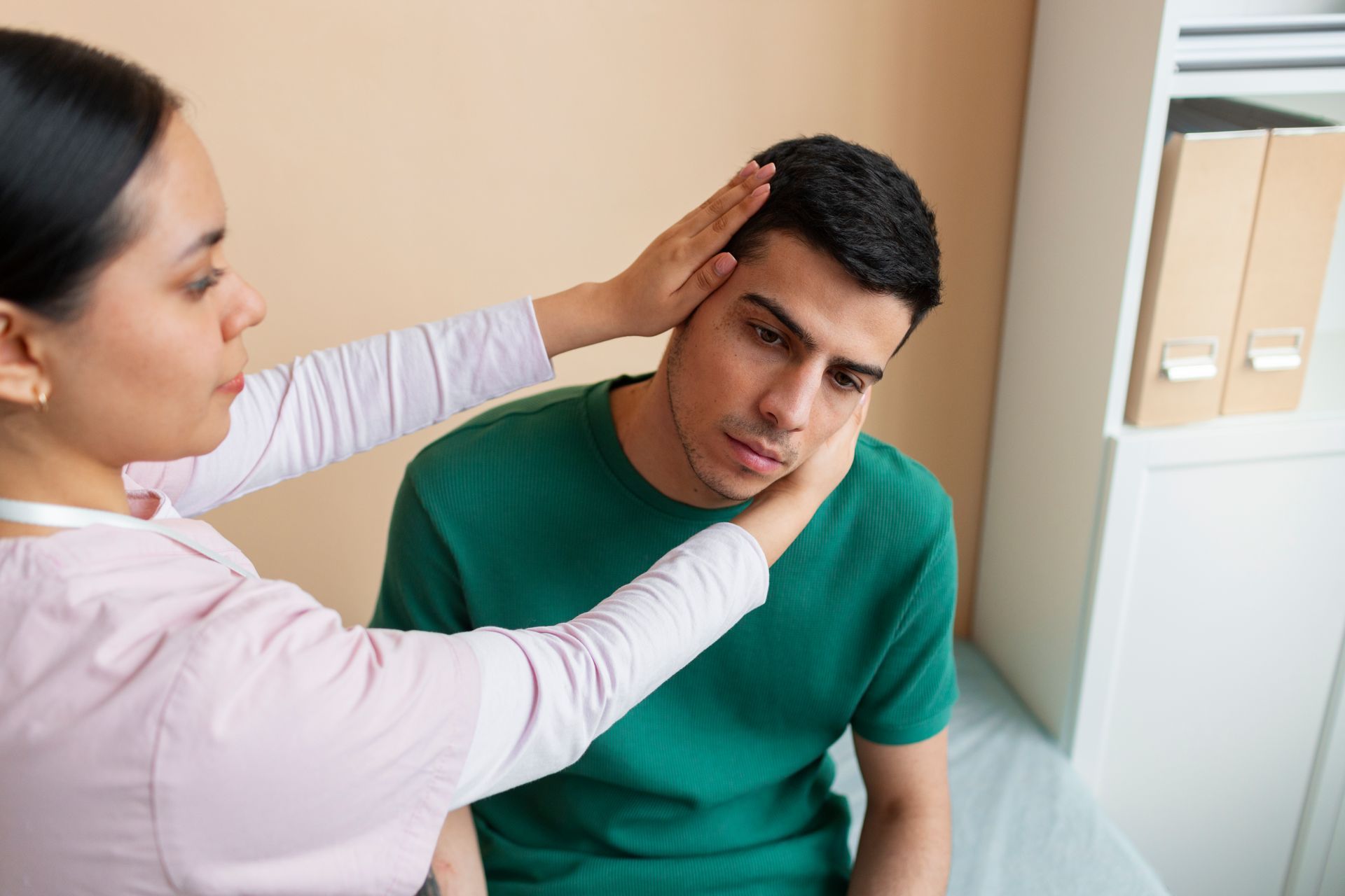 Clinician checks a seated patient’s face and neck in a medical exam room