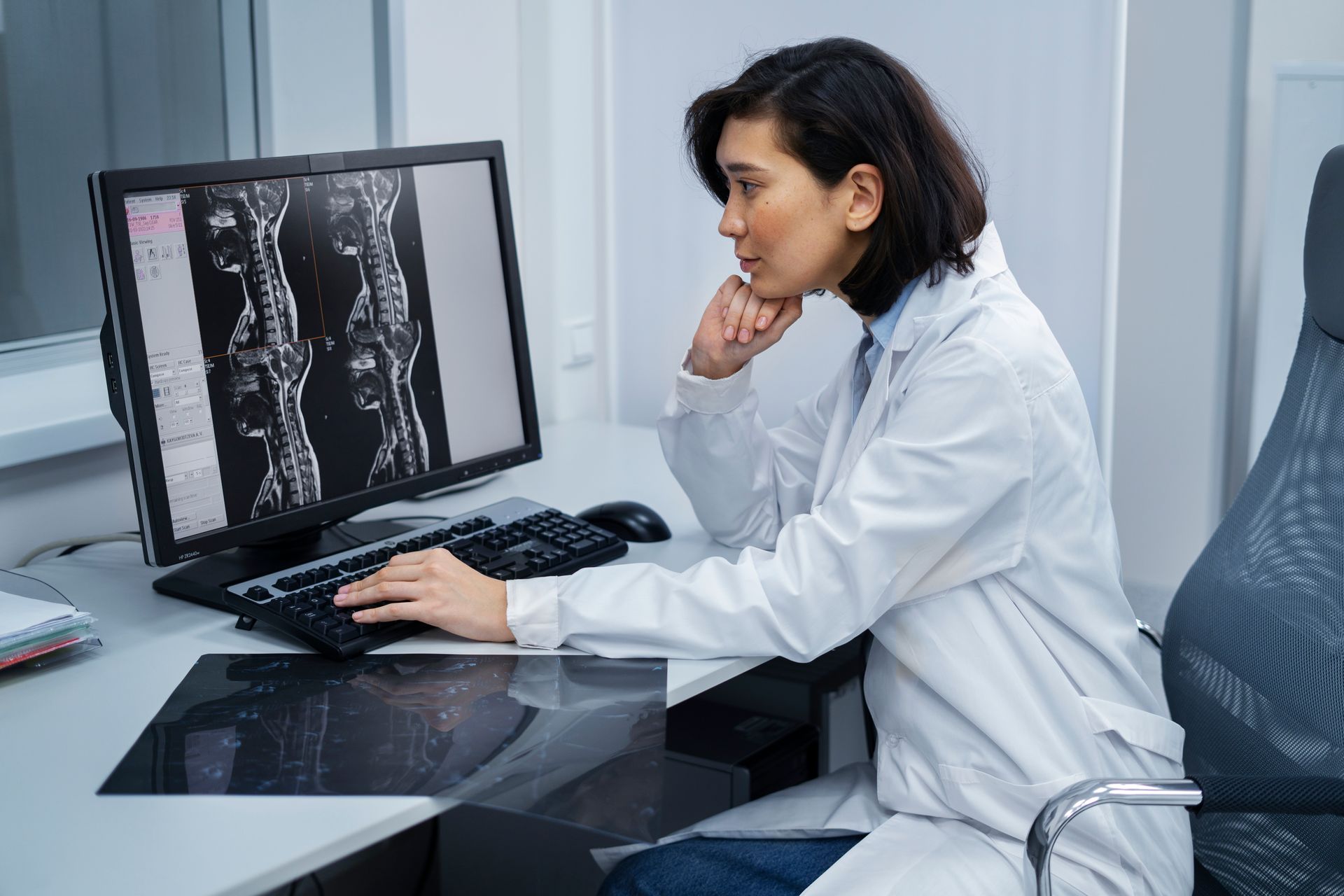 Doctor reviewing spine MRI on a desktop monitor in a clinic office