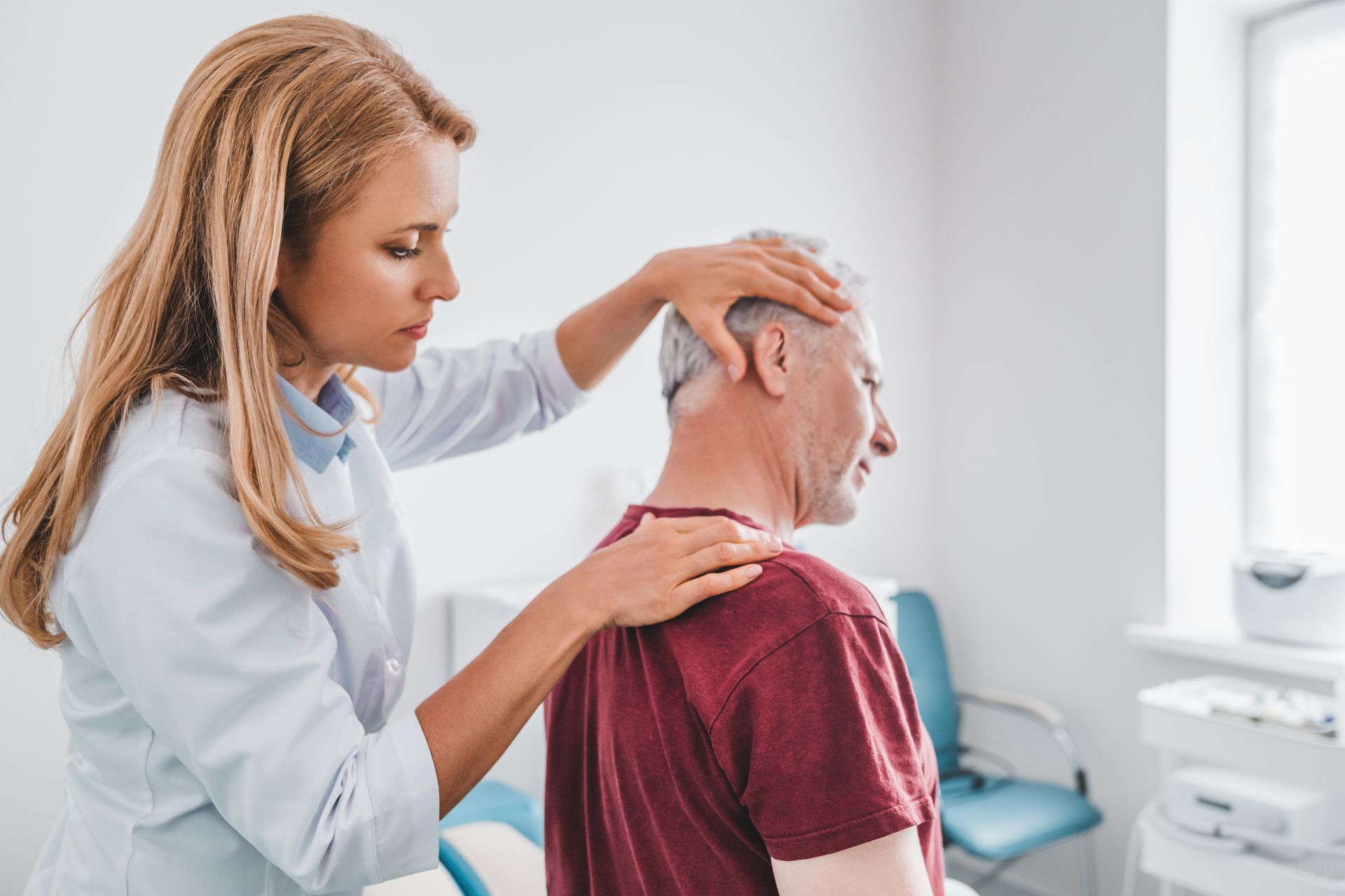 Doctor examining patient’s neck and head in a bright clinic room