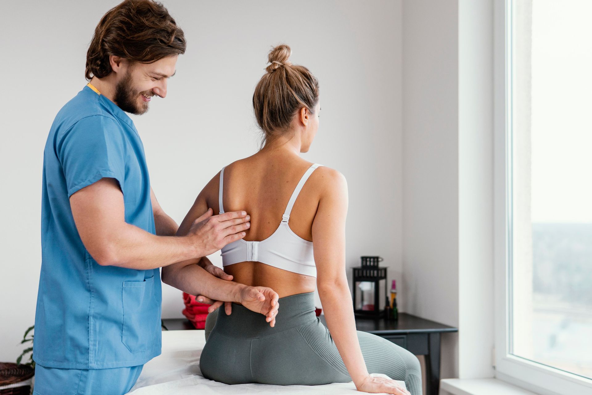 Physical therapist adjusting a woman’s back brace in a bright treatment room