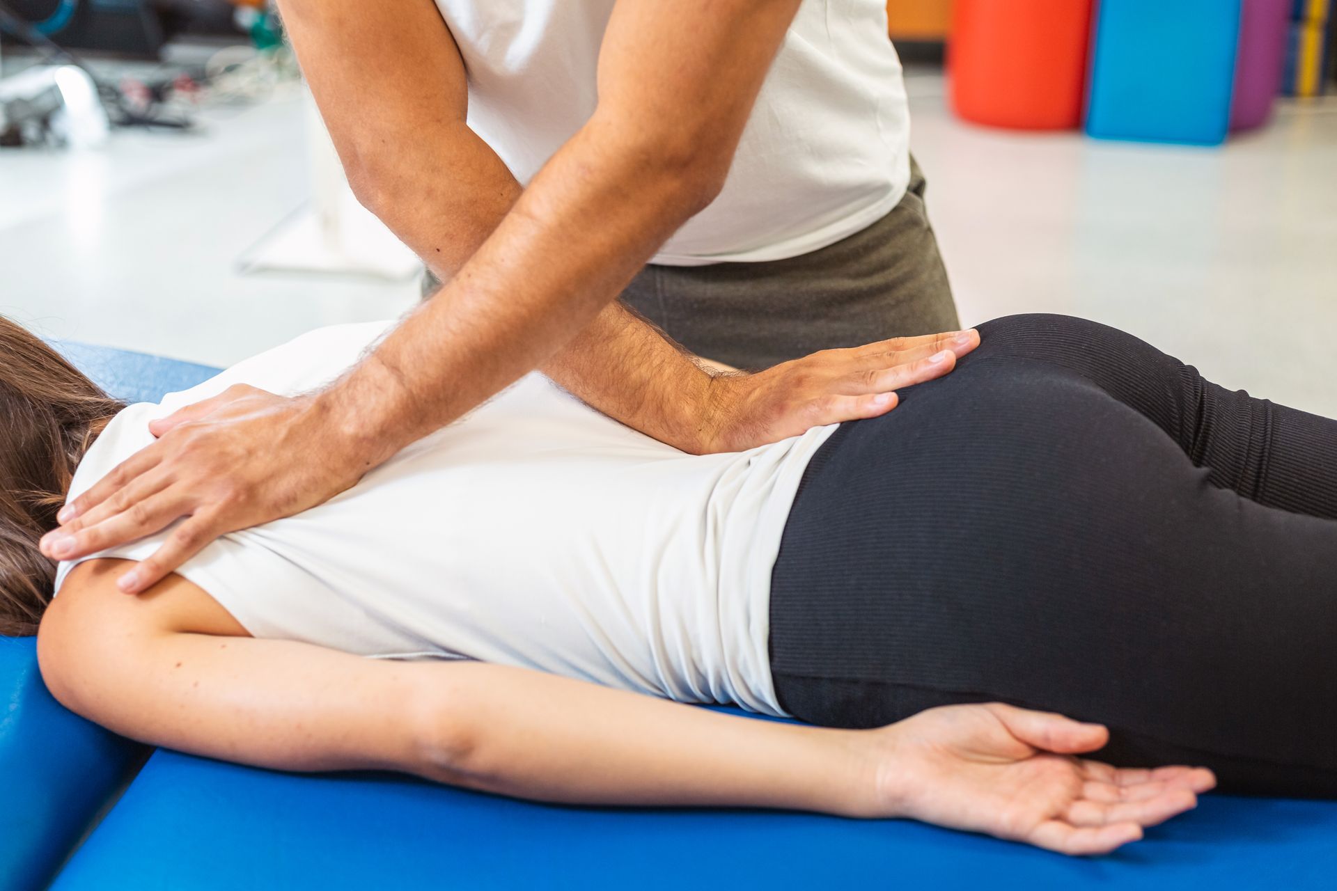 Massage therapist pressing on a person’s back during a treatment on a blue table