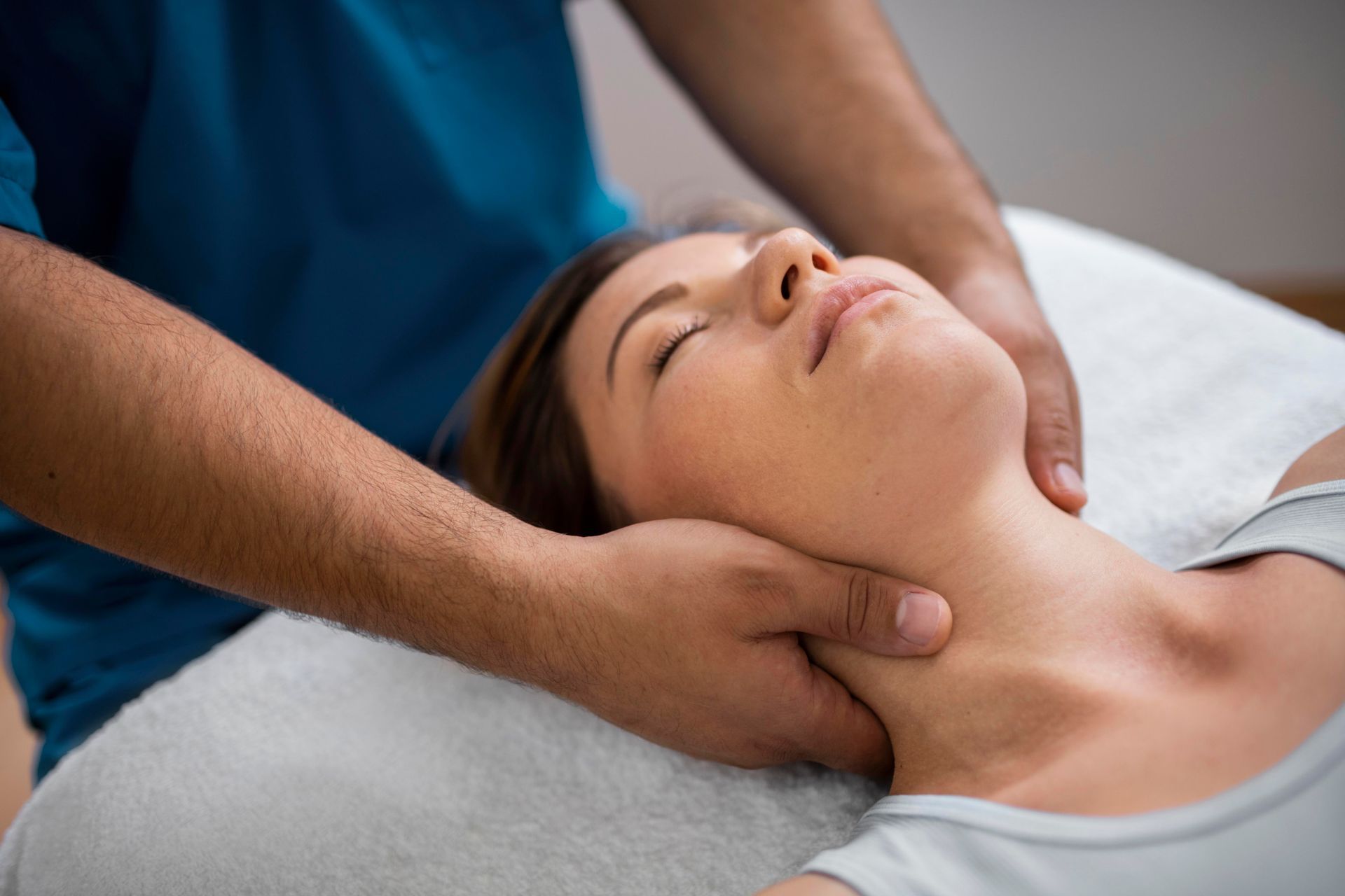Therapist gently massaging a woman’s neck and shoulders on a treatment table