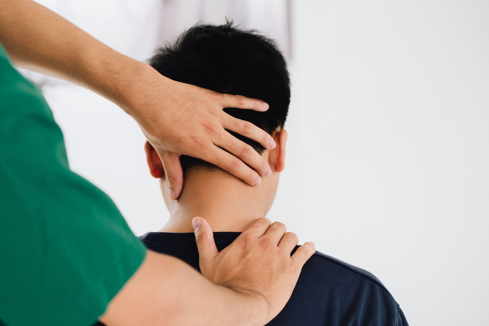 Person receiving a neck massage from a therapist in a green shirt