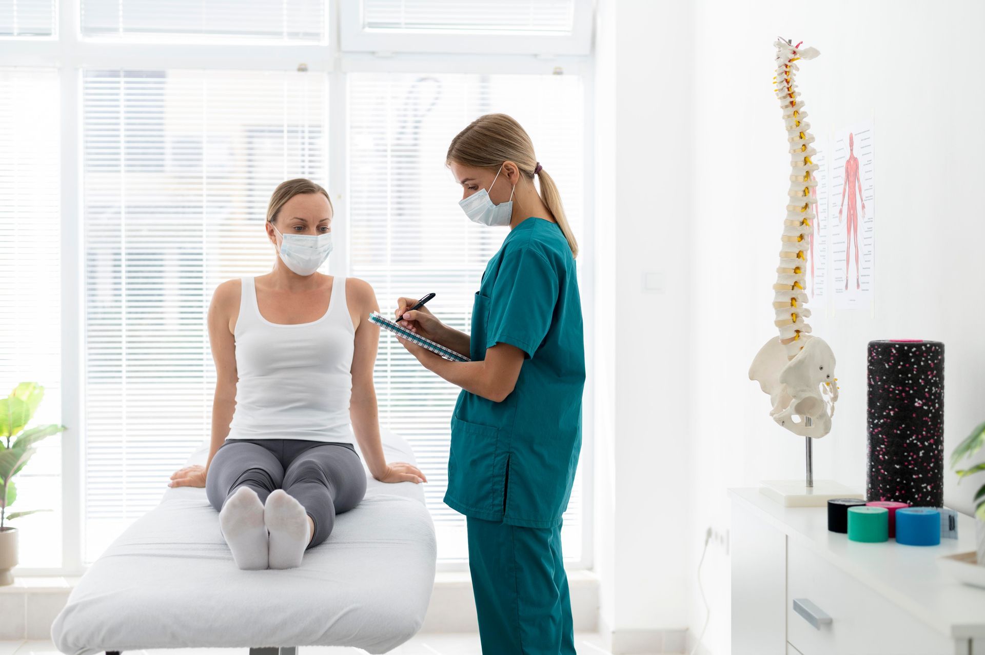 Patient seated on exam table as clinician takes notes in a bright medical office