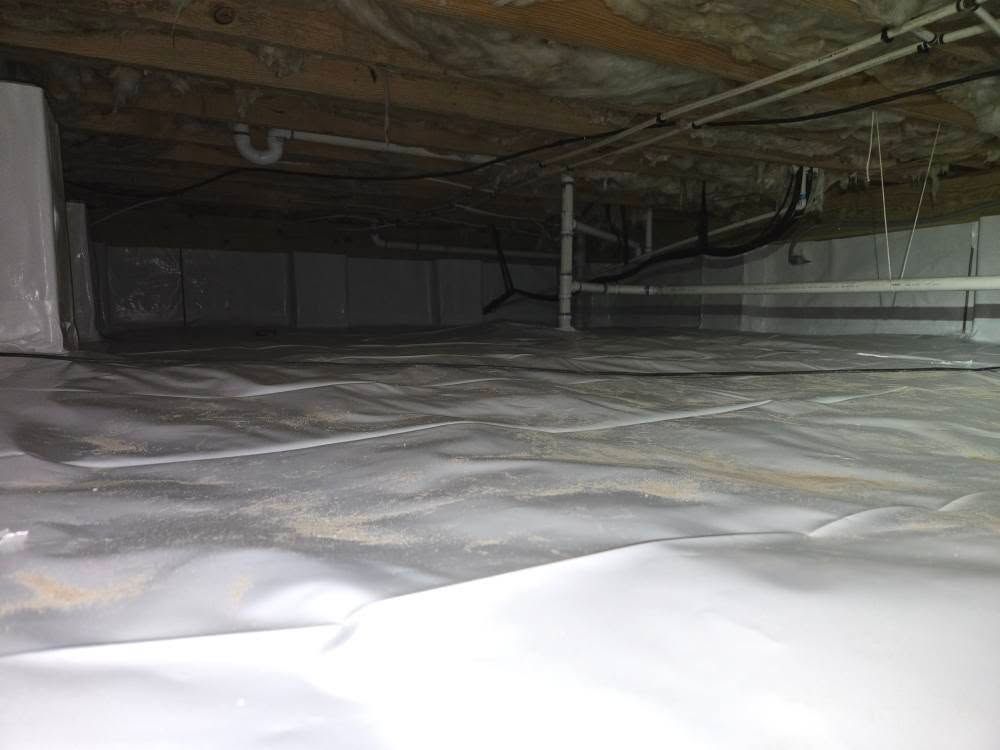 Insulated attic crawlspace with exposed beams, ducts, and white vapor barrier flooring