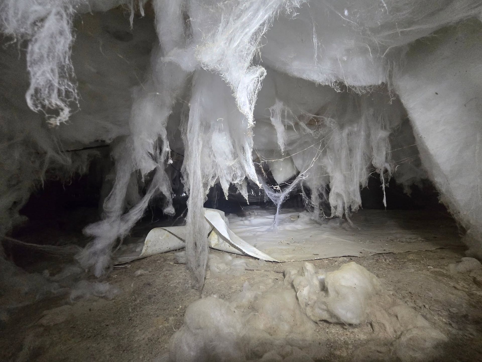 Ice cave with hanging icicles and frozen formations over a rocky floor