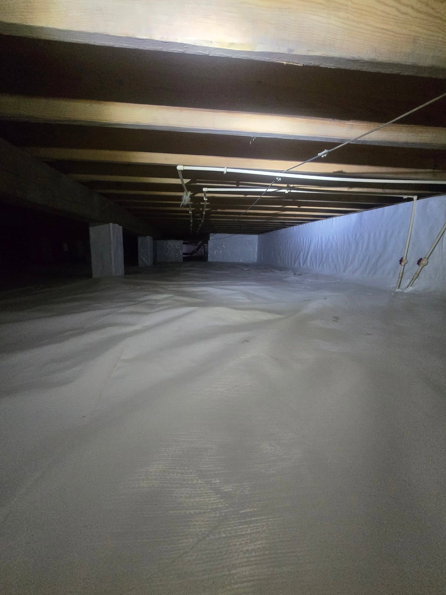 Snow-covered understructure with wooden beams overhead and a snowbank along the right wall.