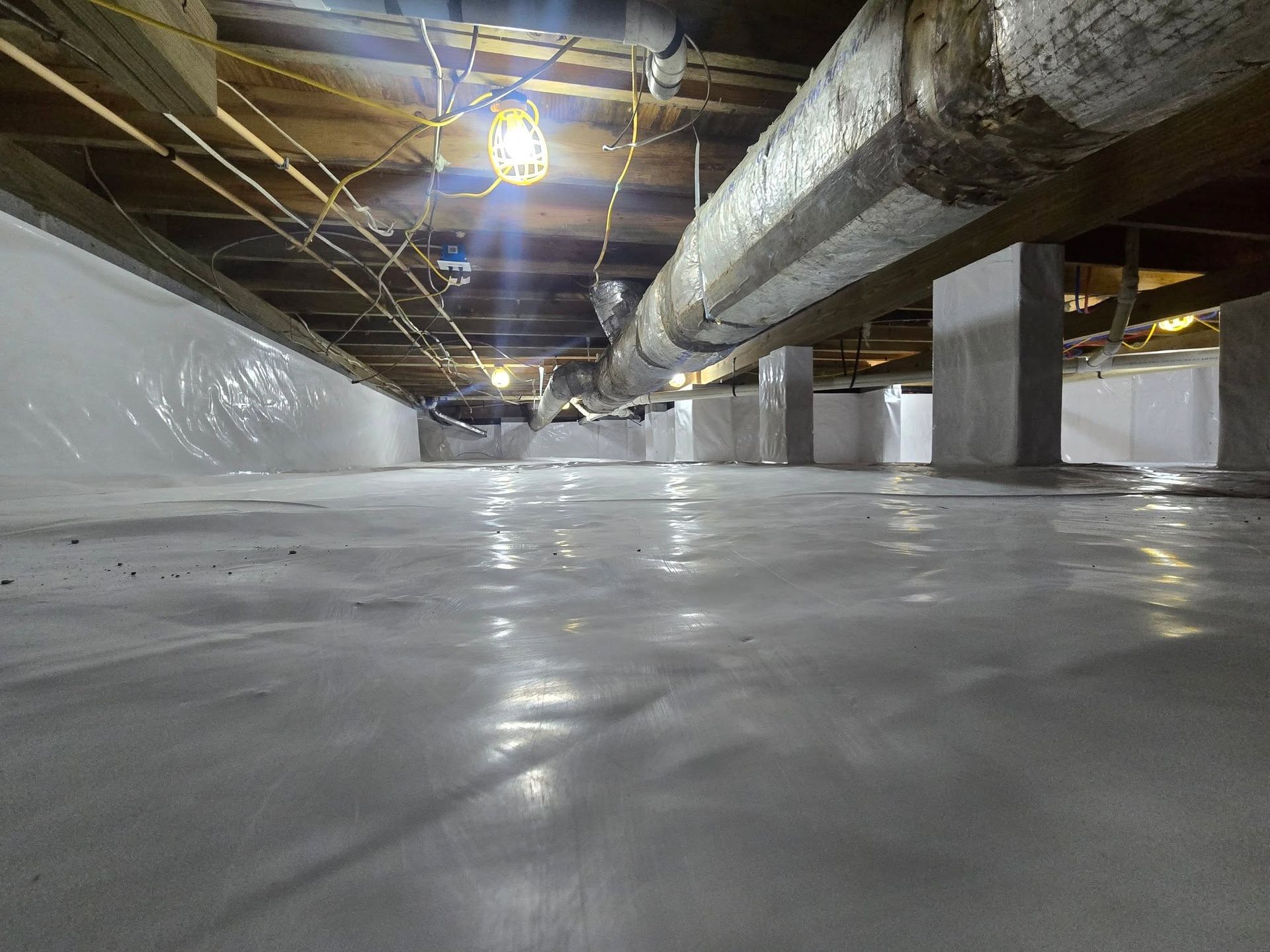 Low-angle view of an empty industrial basement with ducts, pipes, columns, and a sealed floor