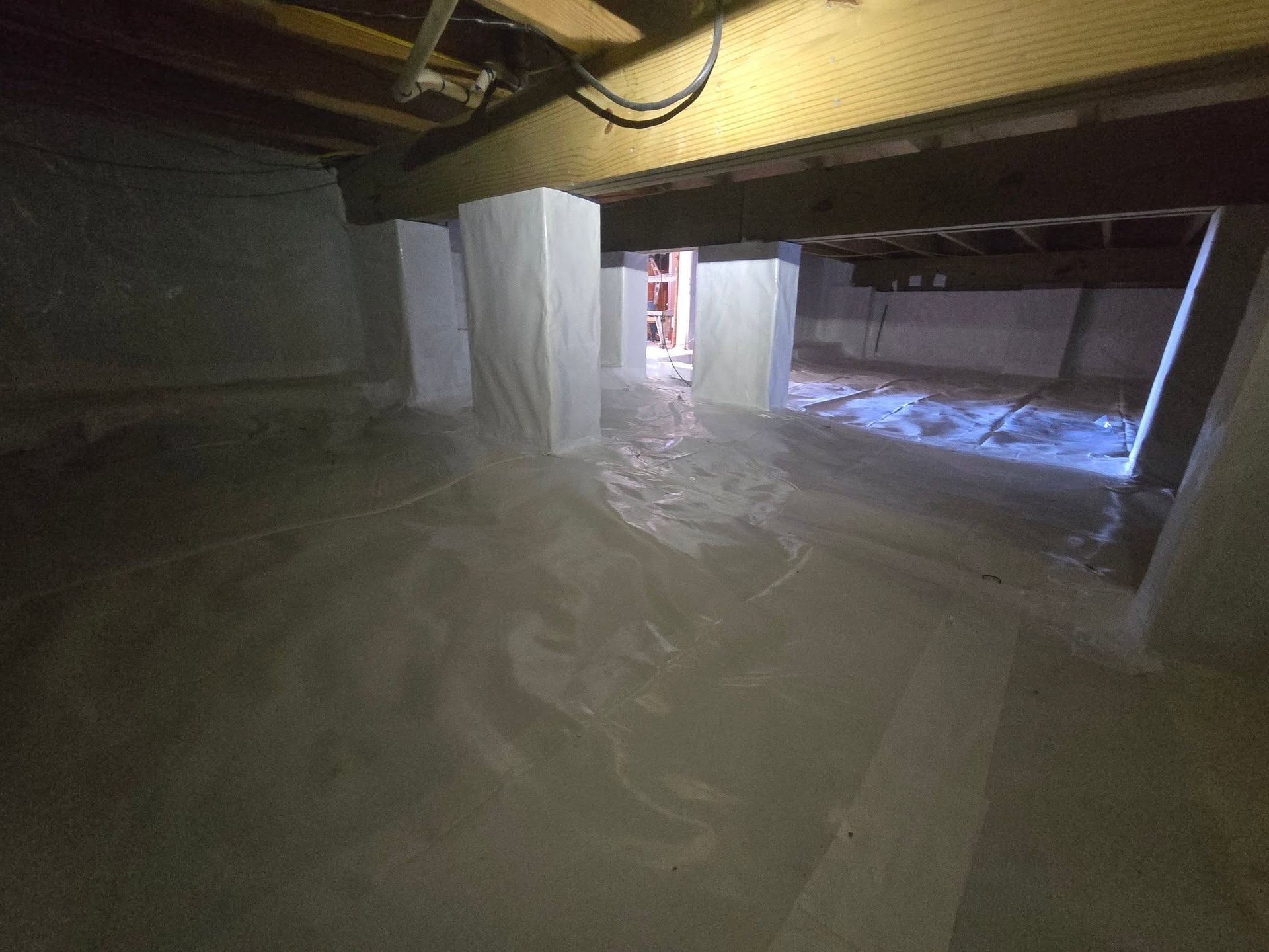 Flooded basement with standing water, concrete pillars, and a lit doorway in the distance