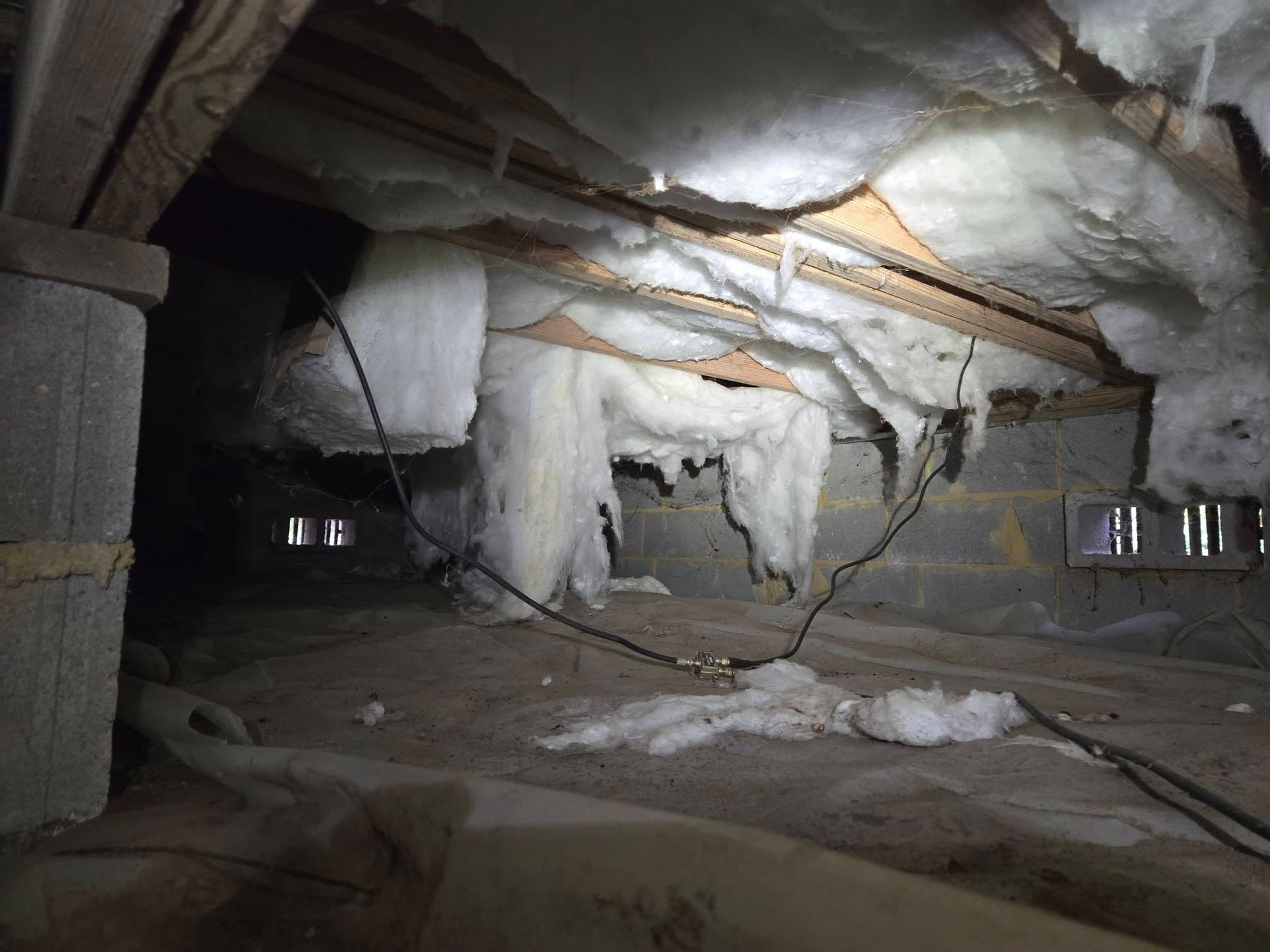 Cave-like interior with white rock or insulation draped over walls and ceiling, lit by a bright overhead light