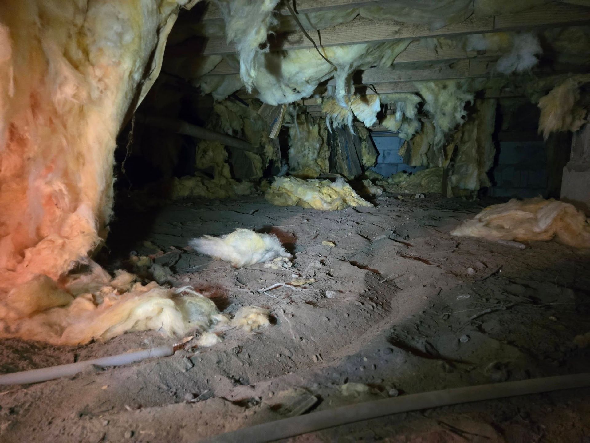 Cave tunnel with rocky floor, rough icy walls, and scattered snow or ice patches