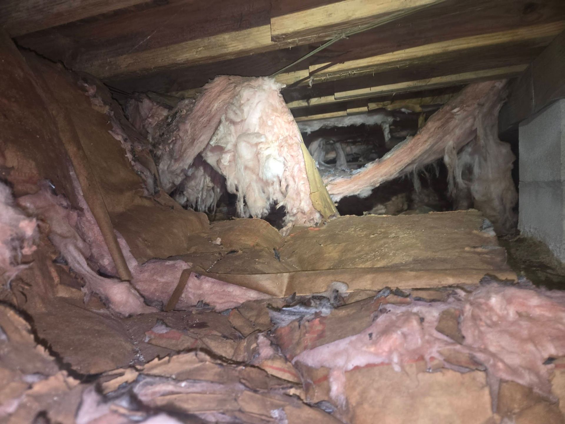 Collapsed attic with exposed wooden beams and pink insulation rubble