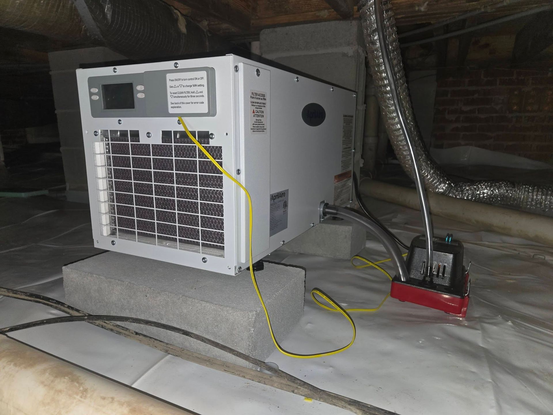 Portable HVAC unit in an attic, with yellow and red hoses connected and ductwork nearby