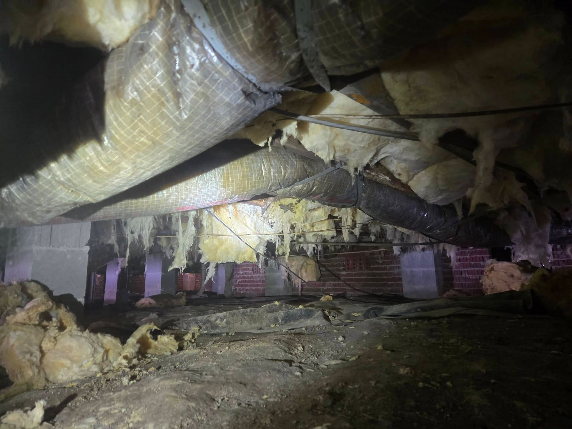 Damaged basement with collapsed insulation, rubble, and dim purple lighting