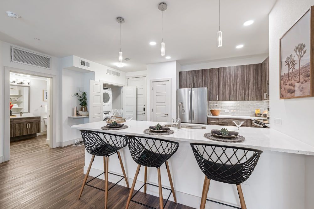 Bright modern kitchen with white island, black barstools, stainless appliances, and recessed ceiling lights