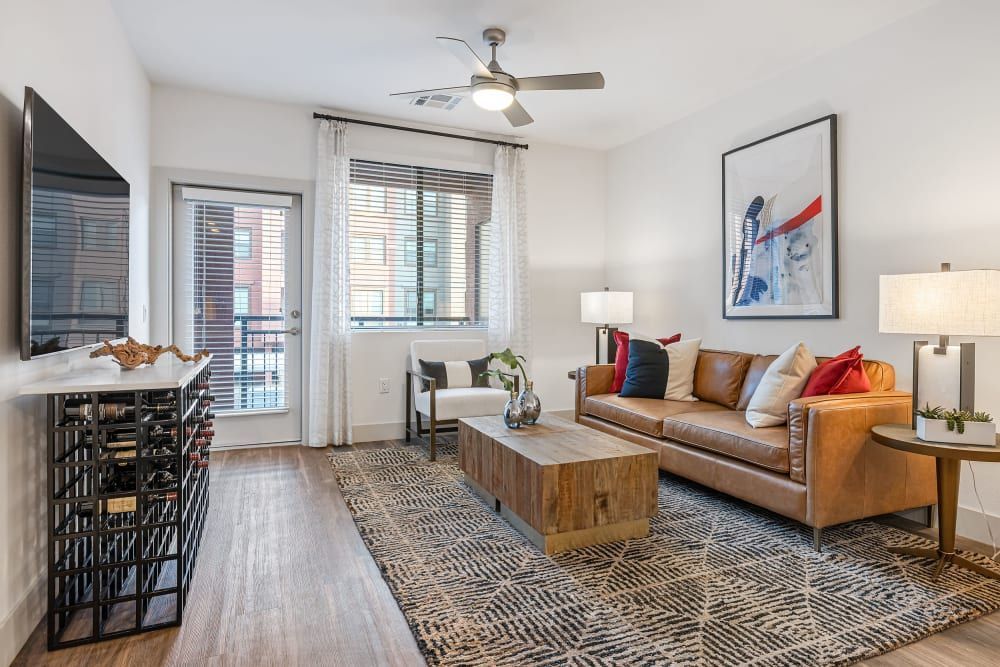 Bright living room with tan sofa, coffee table, patterned rug, wall art, and sliding glass doors