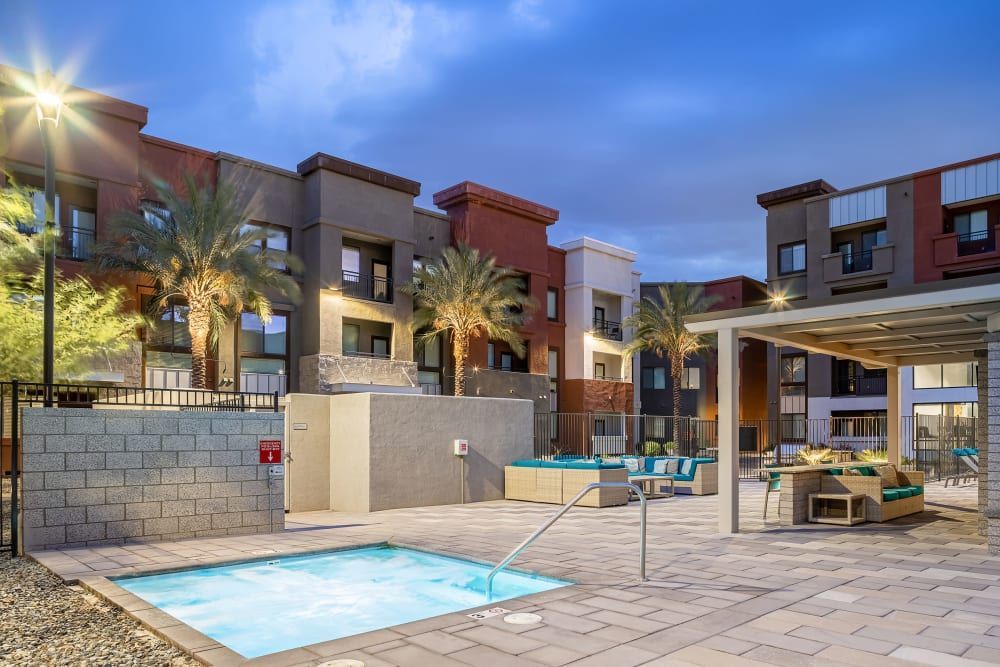 Modern apartment courtyard with a small pool, lounge chairs, and warm evening lighting