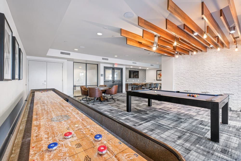 Modern game room with shuffleboard, pool table, and exposed wood ceiling beams